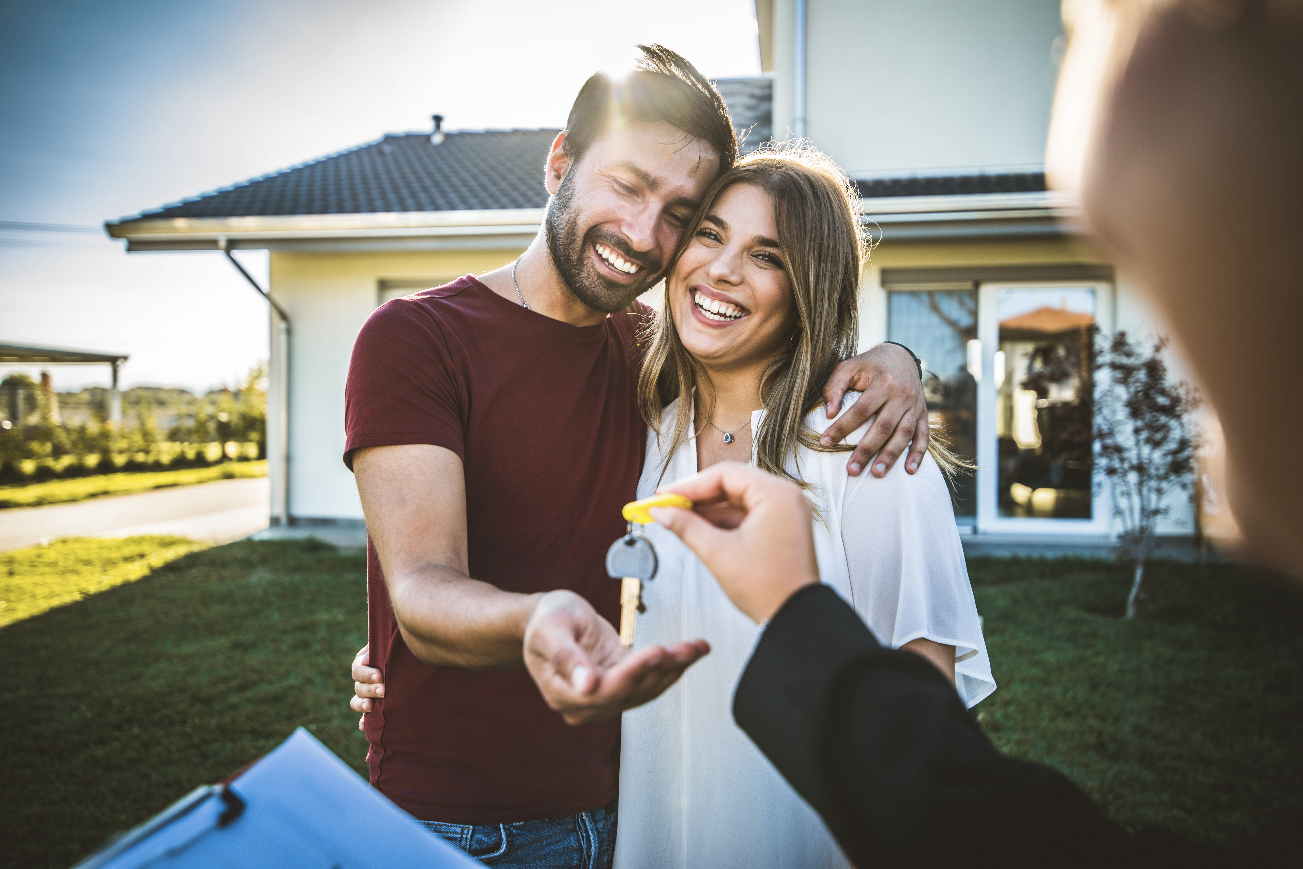Happy millennial couple receiving keys from realtor, purchasing real estate